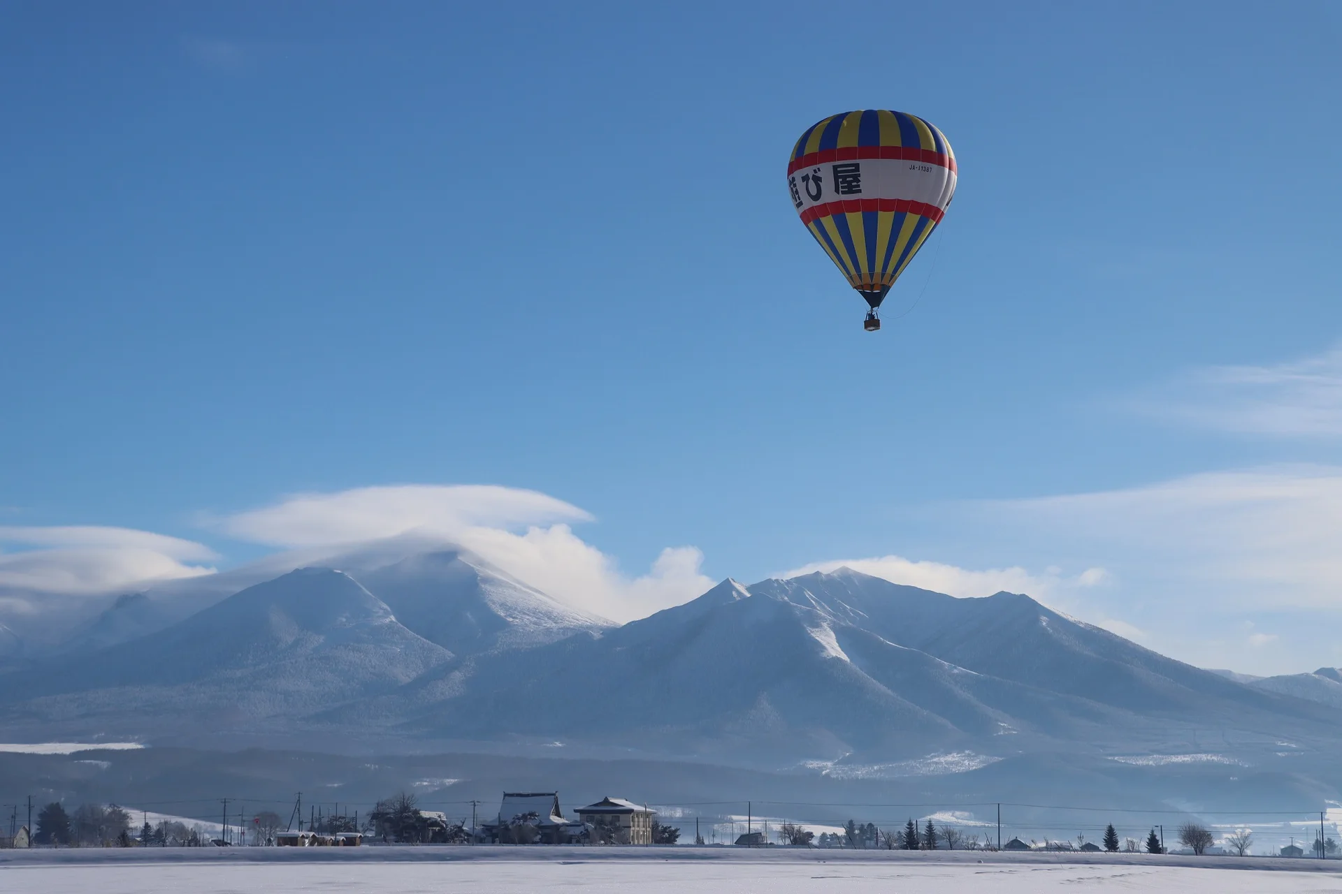 A Furano winter hot air balloon Free Flight over snowy fields. The value is genuine wind-driven travel and a 360-degree winter view, not simply a longer version of the summer ride.