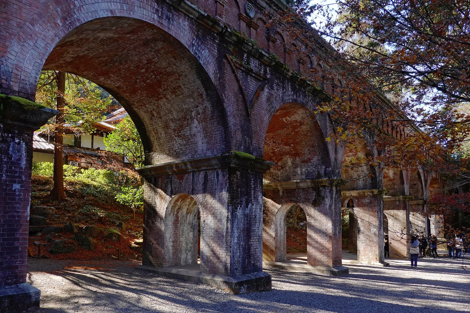 Nanzenji aqueduct framed by autumn leaves for lens compression, architecture and crowd simplification