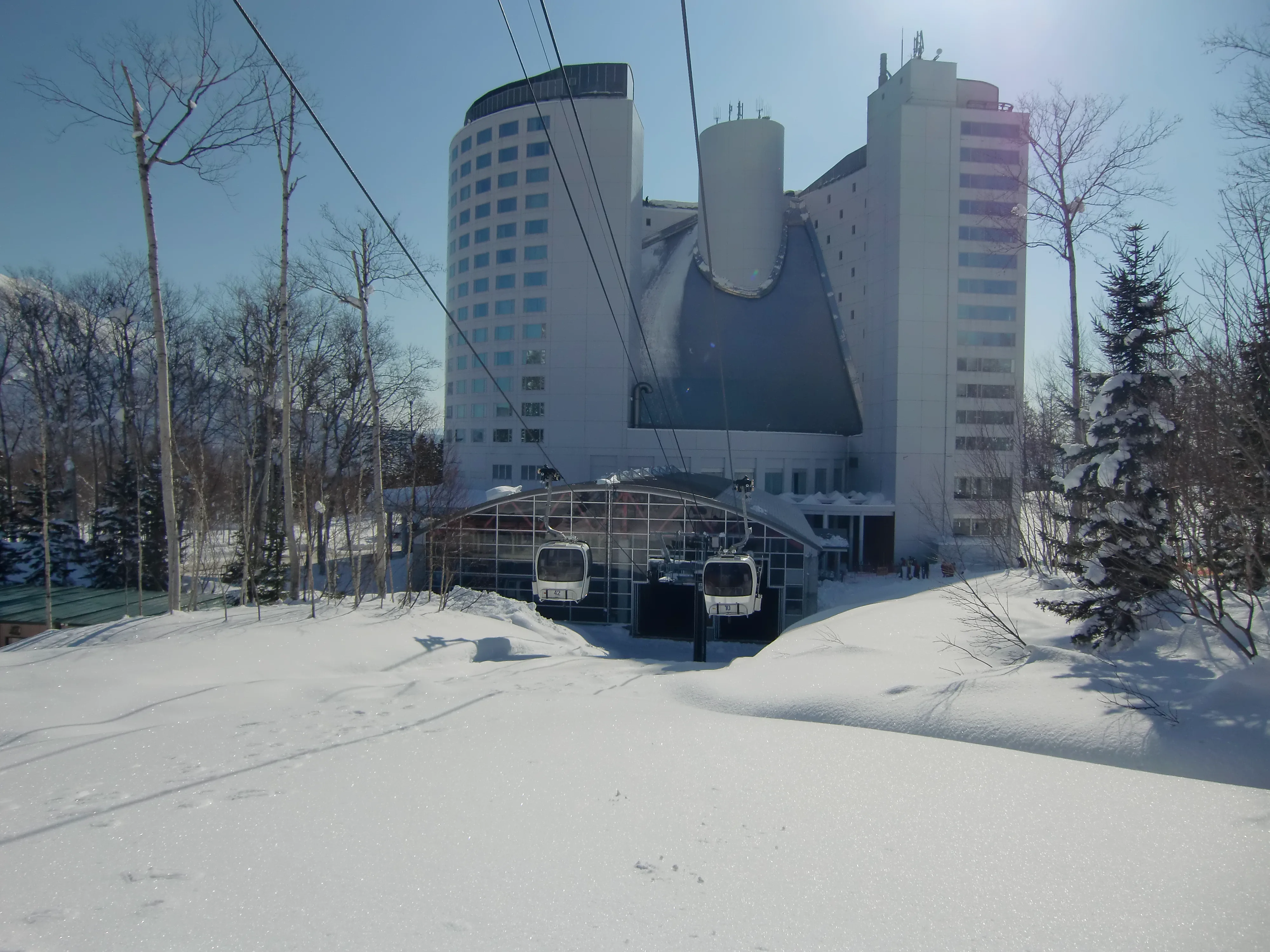 Niseko Village gondola and resort hotel area, illustrating a resort-bundle ski base with dining and onsen close together