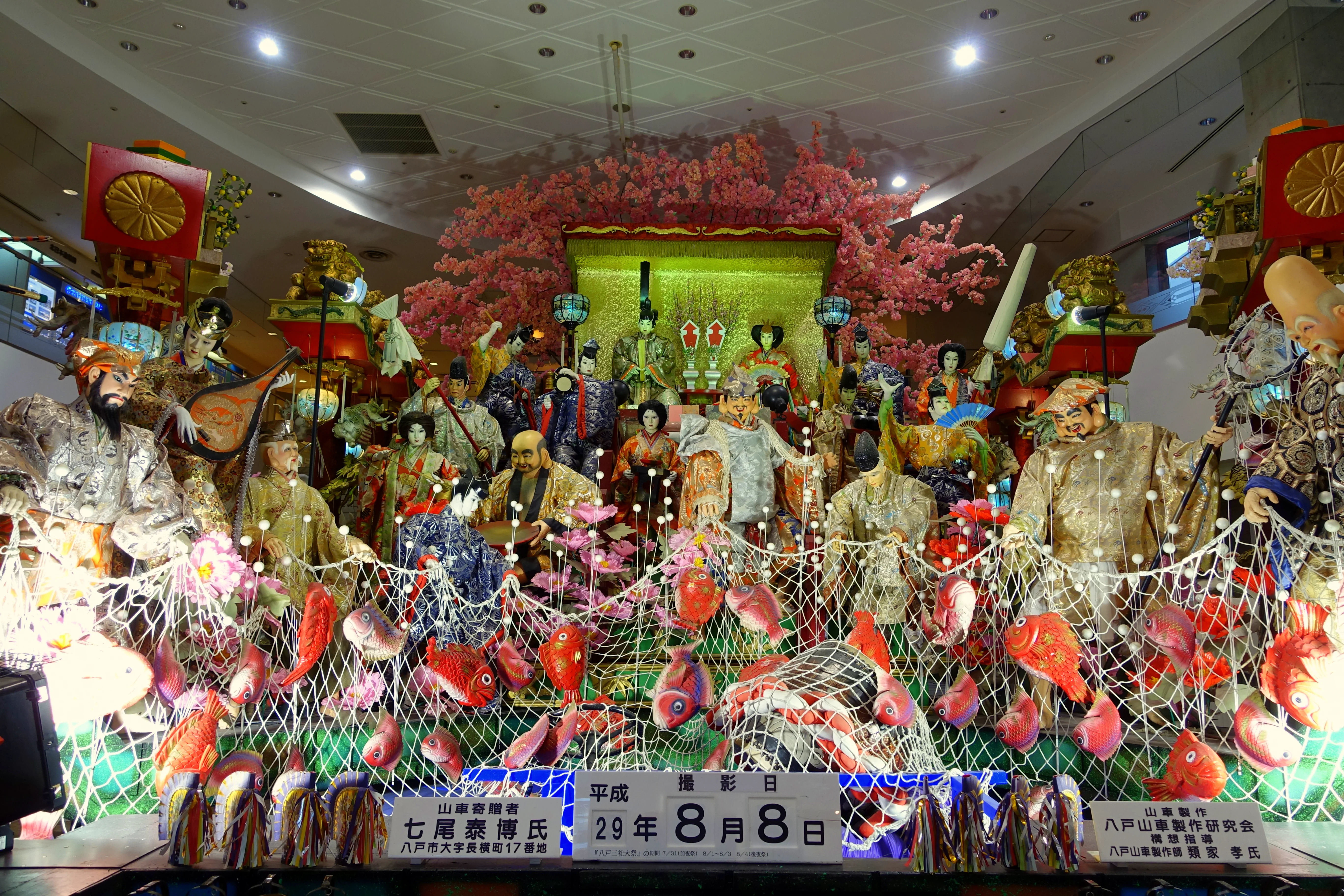 Illuminated Hachinohe Sansha Taisai dashi with layered figures and spectators at night