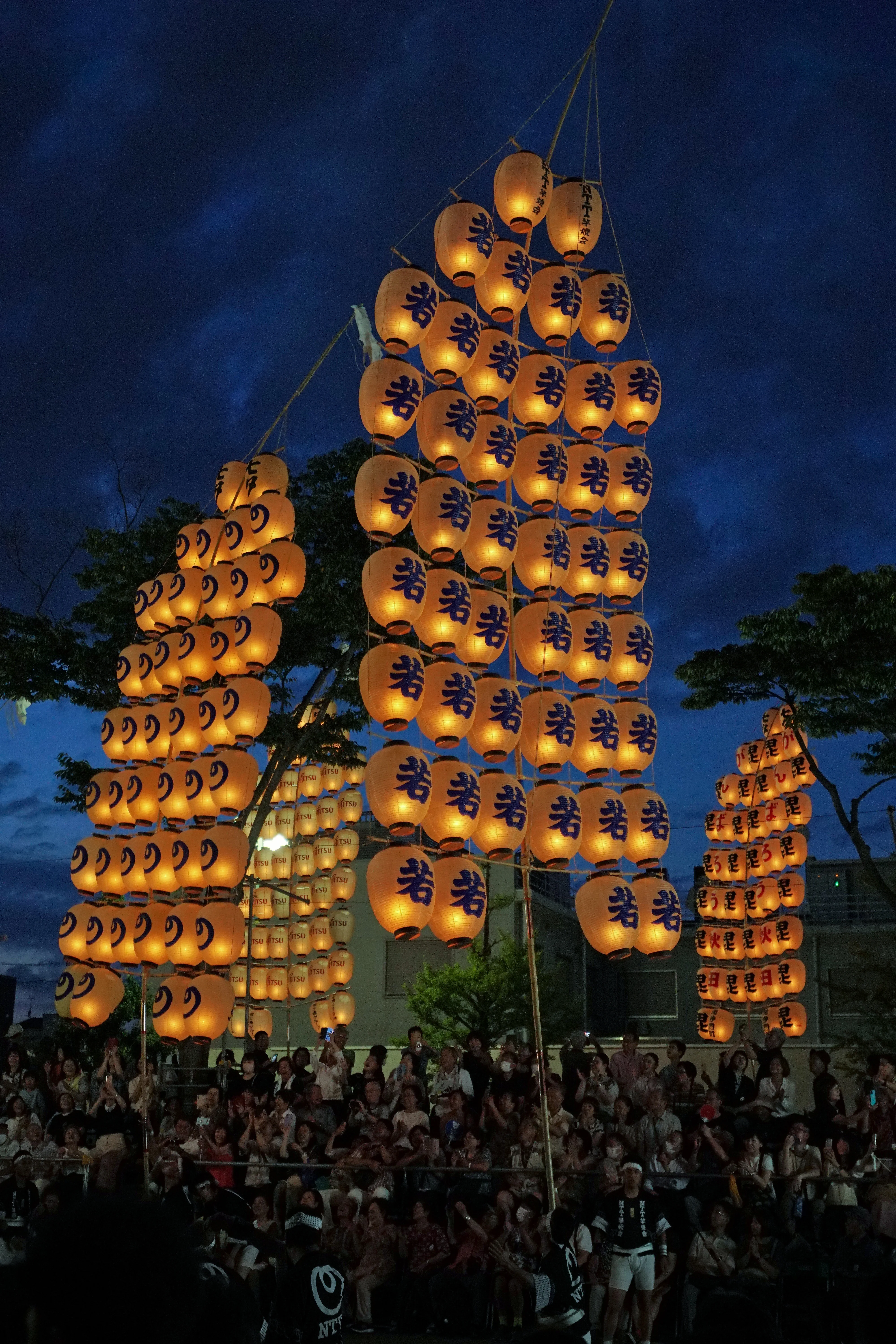 A performer balancing a towering illuminated lantern pole during the Akita Kanto night programme