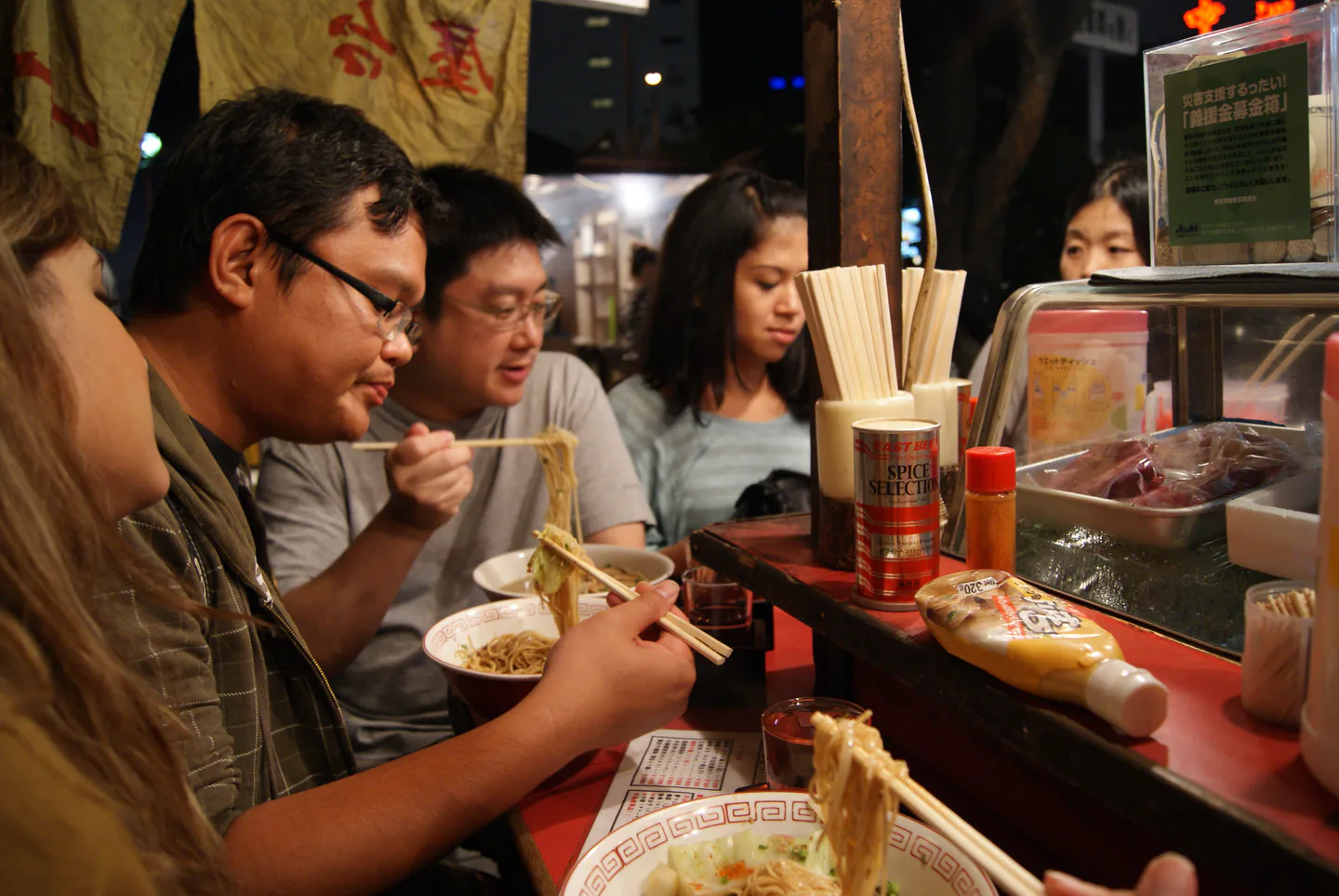Fukuoka yatai food stalls beside the river with diners seated at the counter